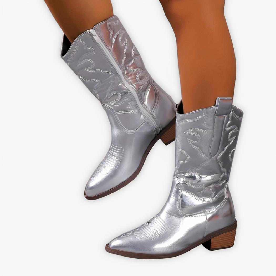 Santiag argentée à talon et broderies élégantes portée par une femme sur fond gris