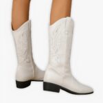 Santiag blanche élégante et mi haute avec broderies portée par une femme sur fond gris