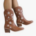Santiag courte femme style cowboy avec motifs étoiles, de couleur marron, porté par une femme sur un fond gris.
