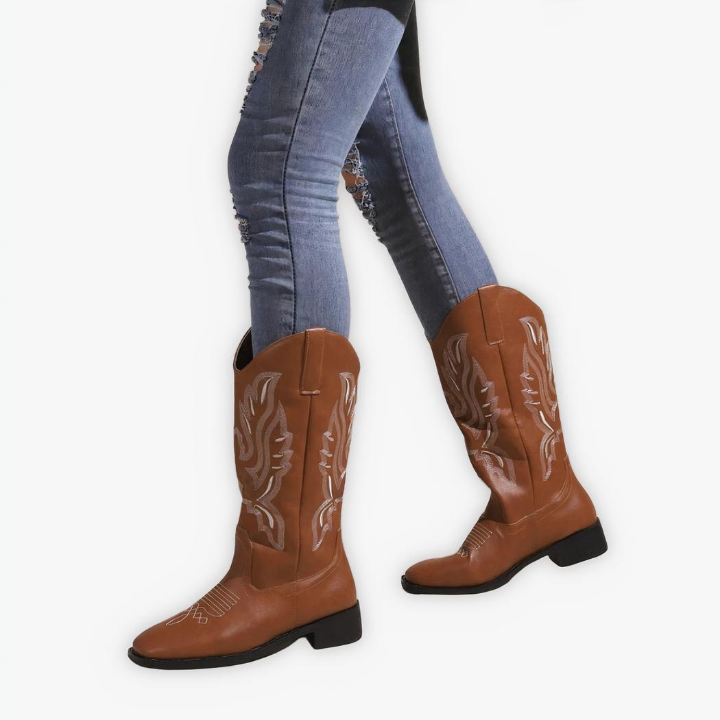 Santiag femme mollet large en simili cuir marron, porté par une femme avec un jean, sur un fond gris