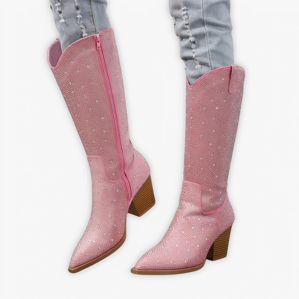 Santiag rose haute à strass et talon pour femme, porté par une femme avec un jean bleu sur fond gris