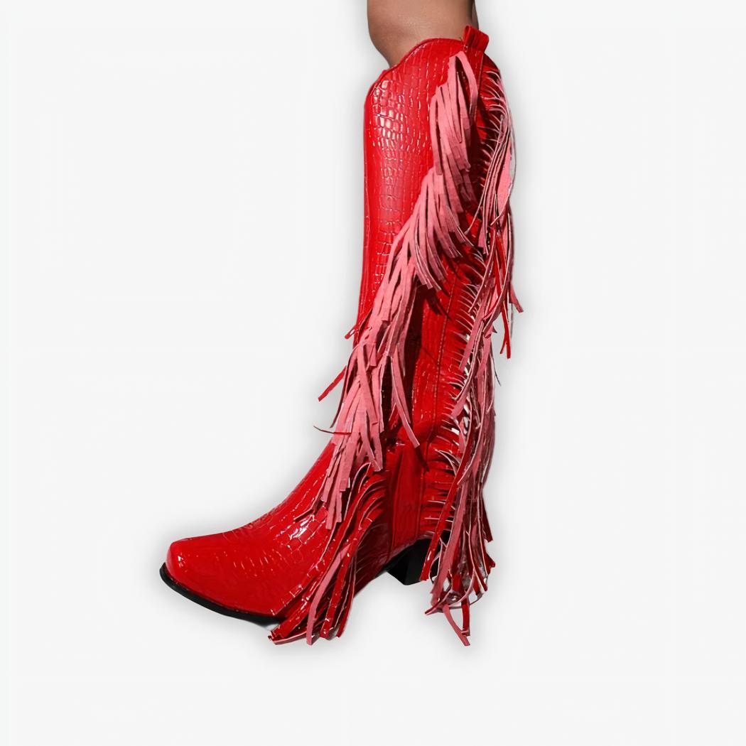 Santiag rouge haute style cowboy à franges pour femme, avec talon, porté par une femme sur un fond gris.